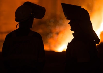 To personer med verneutstyr foran glød