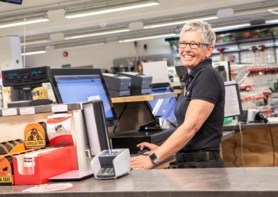 En smilende dame bak disken på Monter