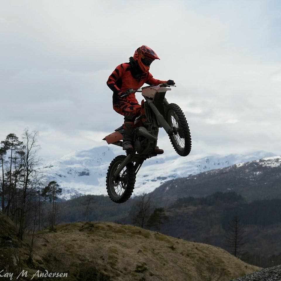 En person på cross motorsykkel midt i ett hopp